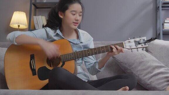 快乐少女在家里的客厅弹吉他创意爱好