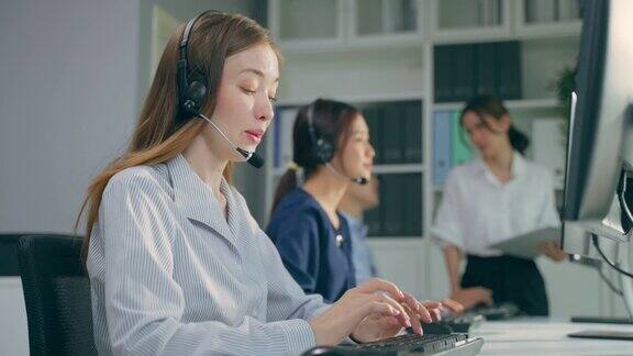 一群美丽的商务女性在办公室公司呼叫中心工作有魅力的年轻员工坐在桌子上戴着耳机使用笔记本电脑在工作场所与客户交谈