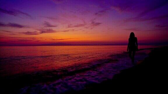 一个女人的剪影享受宁静日落海景从海滩