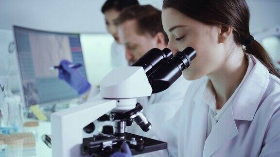 多民族实验室团队处理病原体样本女医生使用显微镜