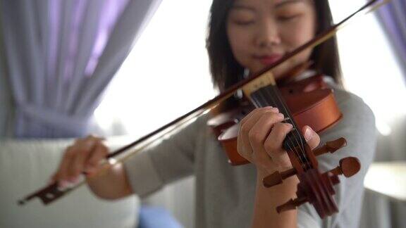 一个在家里拉小提琴的亚洲华人妇女