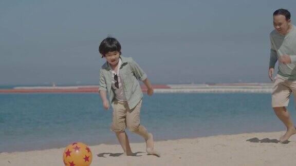 亚洲父亲和儿子在沙滩上踢足球