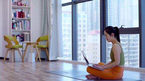 一名年轻的亚洲女子在练习瑜伽后使用笔记本电脑