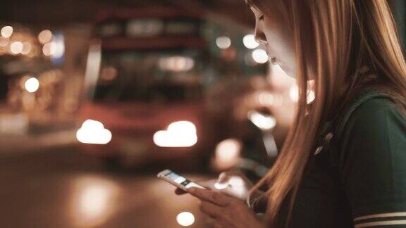 女性在晚上用智能手机请求和等待优步