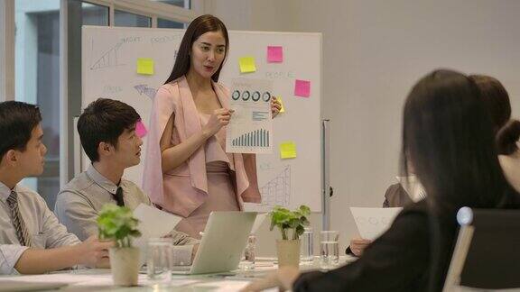 迷人的亚洲女人在会议室向她的团队展示她的商业计划战略发展理念经营理念