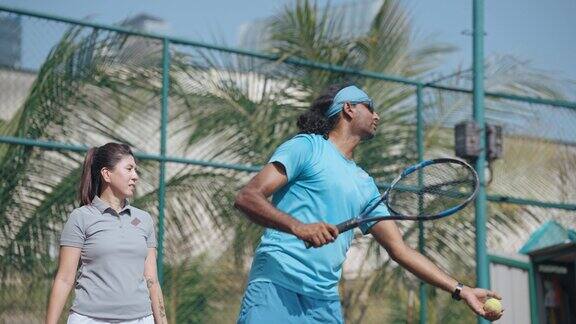 亚洲网球教练在网球场上为他的学生示范