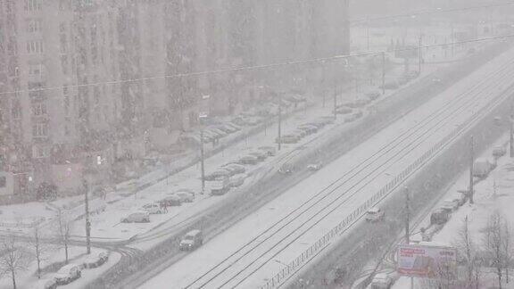 城市街道上大雪纷飞在下雪的街道上车辆川流不息从窗口