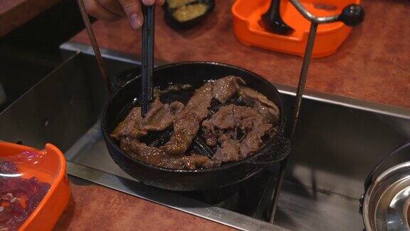在餐桌上用小火烹调切成薄片的牛肉的过程
