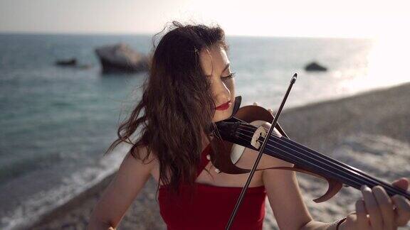 高角度的肖像吸收才华女子演奏小提琴在缓慢的日落在地中海海岸自信专注的高加索女士享受音乐在日落的海岸
