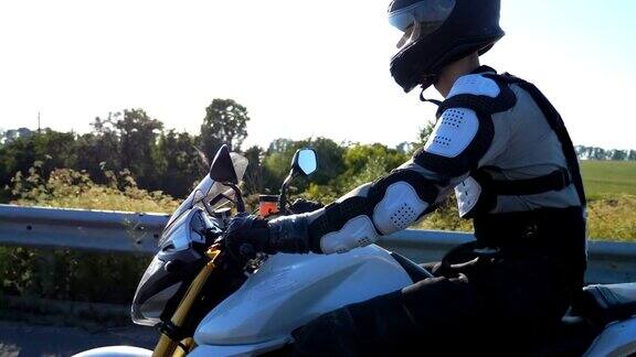 在高速公路上一名戴着头盔的男子骑着强大的摩托车疾驰一名摩托车手在乡村公路上骑摩托车比赛一个骑摩托的家伙在旅途中骑着自行车冒险和自由