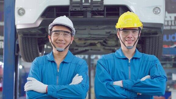两个英俊的亚洲汽车机械师站在车库的肖像汽车维修经理工人在机械厂工作检查和维护后查看摄像头修理发动机车