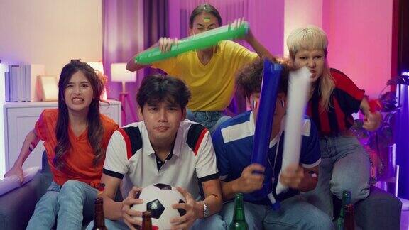 一群快乐的亚洲青少年坐在沙发上一起观看欢呼体育足球比赛世界杯在晚上