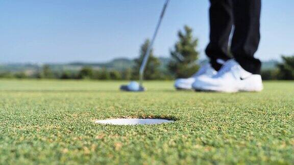高尔夫球手把球推洞在绿色高尔夫球场天空的场景背景