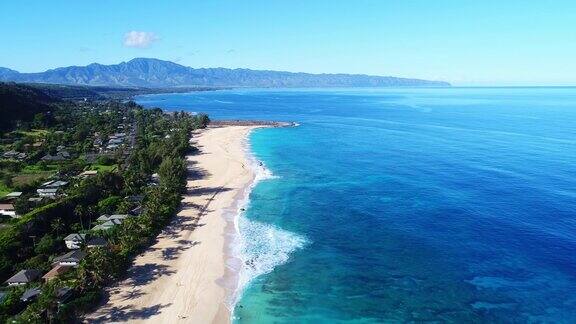 鸟瞰图飞过热带白色沙滩和清澈的蓝色海水在夏威夷北岸在阳光明媚的一天
