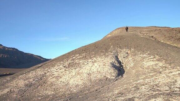 一名女子游客正从美国加州死亡谷的岩石山上走下来