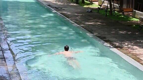 亚洲男子在度假村的游泳池里游泳