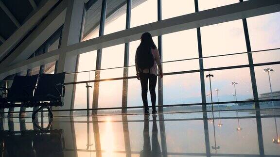 亚洲年轻女子在机场窗口等待航班