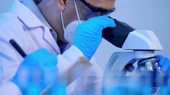 在实验室里通过显微镜进行研究的亚洲科学家