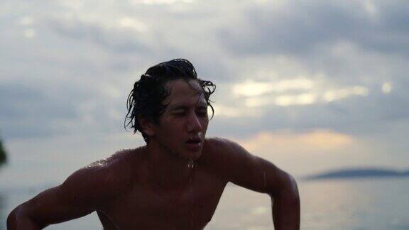 年轻的亚洲男子在夏天日落时的海上冲浪