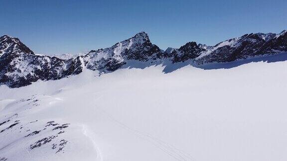 美丽的空中雪山阿尔卑斯山脉冰川高峰冰雪覆盖的滑雪冬季运动仙境在阳光明媚的日子无人机在雪坡上飞行