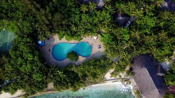 俯瞰马尔代夫岛相机在豪华酒店的游泳池上方升起航拍的度假村有很多棕榈树、平房、海滩和印度洋从上面的观点