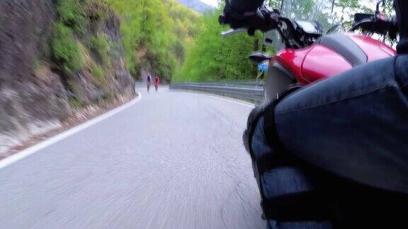 骑摩托车的人沿着风景优美的山路在意大利侧视图观点
