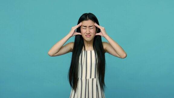 头疼痛不健康生病的亚洲妇女与长黑发摩擦太阳穴遭受严重的头痛