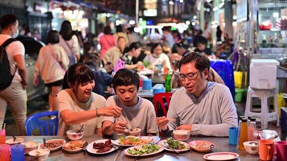 4K亚洲家庭在曼谷唐人街的街头餐馆吃食物与交通