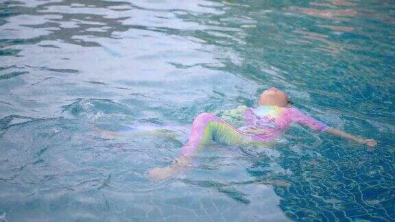 这个女孩平静地漂浮在游泳池里游泳
