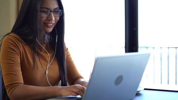 女性在工作或学习时戴着耳机用笔记本电脑听在线会议