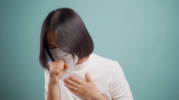 一名亚洲妇女戴着卫生口罩喉咙痛在蓝色背景下孤立地站着4k的视频卫生保健