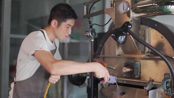 亚洲华人工人用手套吹咖啡用真空吸尘器清洗咖啡烘焙机