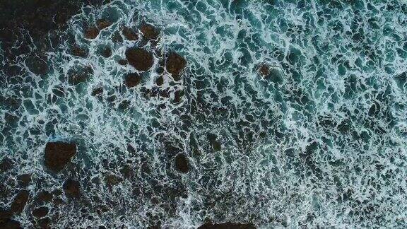 无人机拍摄的海浪冲上海滩的岩石