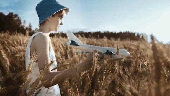 电影中的男孩戴着帽子在金色的麦田里玩飞机移动的相机稳定的镜头