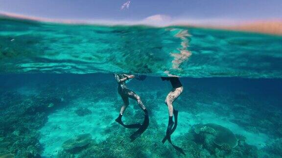 在印度尼西亚的珊瑚礁上自由潜水在印度尼西亚的科莫多国家公园两名女性自由潜水者在自由潜水后在水面上休息