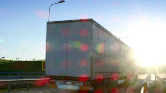 一辆白色半挂车与货物拖车在桥下立交桥下行驶的后续镜头