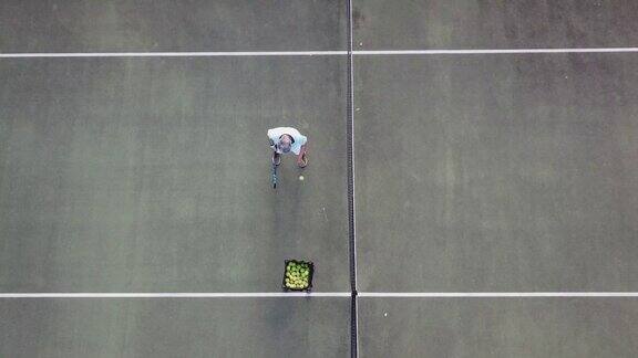 无人机的观点亚洲资深男子网球运动员发球练习在网球场正上方