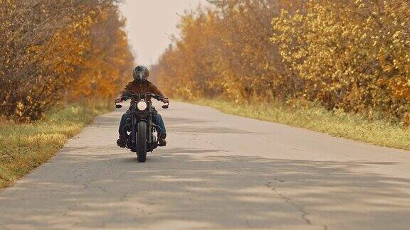 一个骑摩托车的家伙在高速公路上骑着摩托车金色的秋天