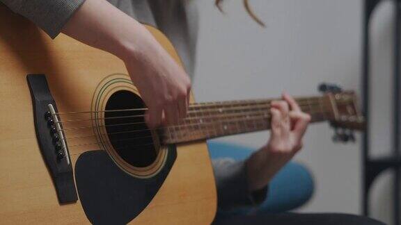 少女左手弹吉他在她的房间与白色的墙壁特写镜头