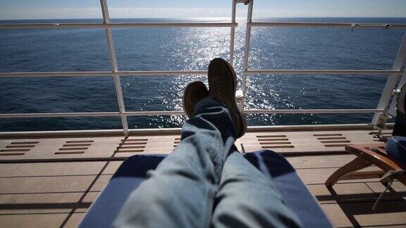 游客在游轮主甲板上享受阳光灿烂的一天躺在木制躺椅上看鲸鱼