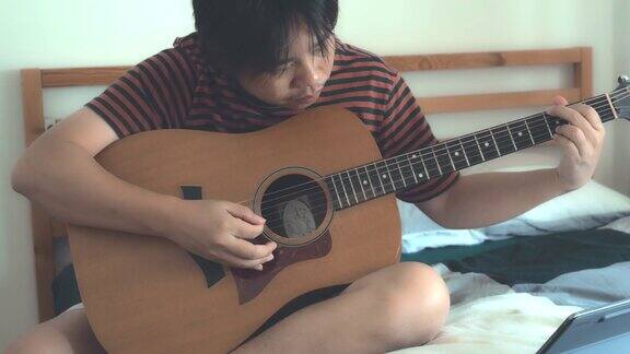 一个年轻人在家里弹吉他