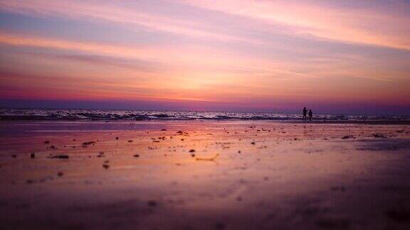黄昏时分母亲和太阳漫步在美丽的沙滩上