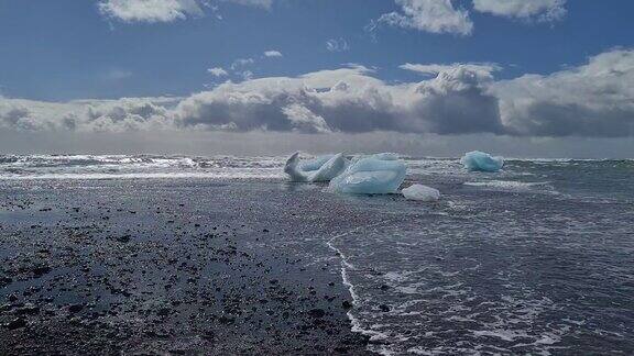 阳光明媚的黑沙滩上的冰川冰全景图
