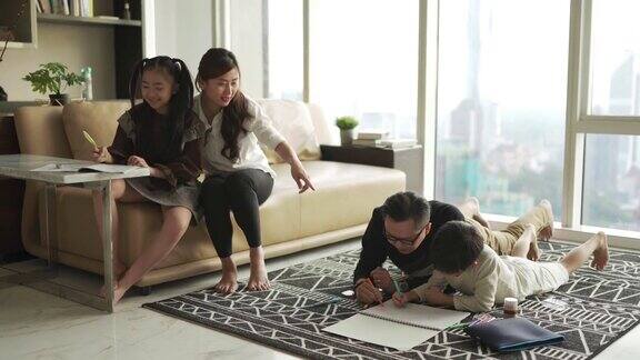 一个年轻的亚洲华人家庭周末在家里的客厅公寓里做作业和画画
