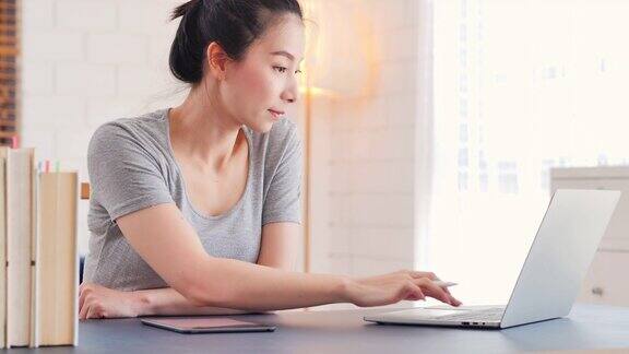亚洲美丽的女人在休闲服装使用平板电脑为她的工作在家工作远程工作和自我隔离新的家庭办公室设置