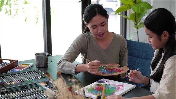 年轻的亚洲老师在美术课上和亚洲女孩一起画画