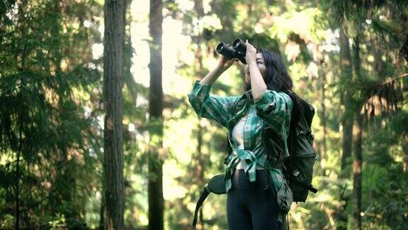 在森林里用双筒望远镜的年轻女子