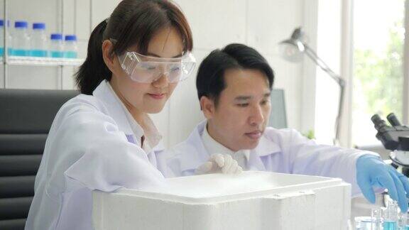 医学研究科学家从科学研究实验室的低温氮容器中取出装有冷冻细胞样本的培养皿她在一个繁忙的现代化实验室中心工作