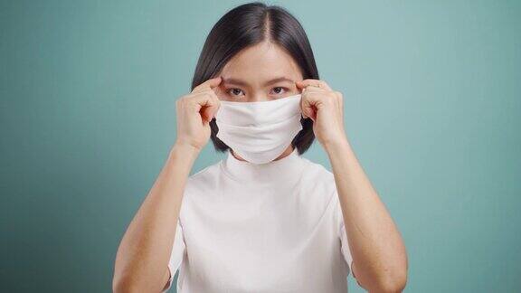 亚洲妇女戴防护口罩以防止病毒和疾病在蓝色背景上被隔离COVID-19冠状病毒