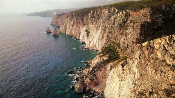 无人机拍摄的希腊扎金索斯的爱奥尼亚海岸岩石峭壁植被蓝色的海水日落